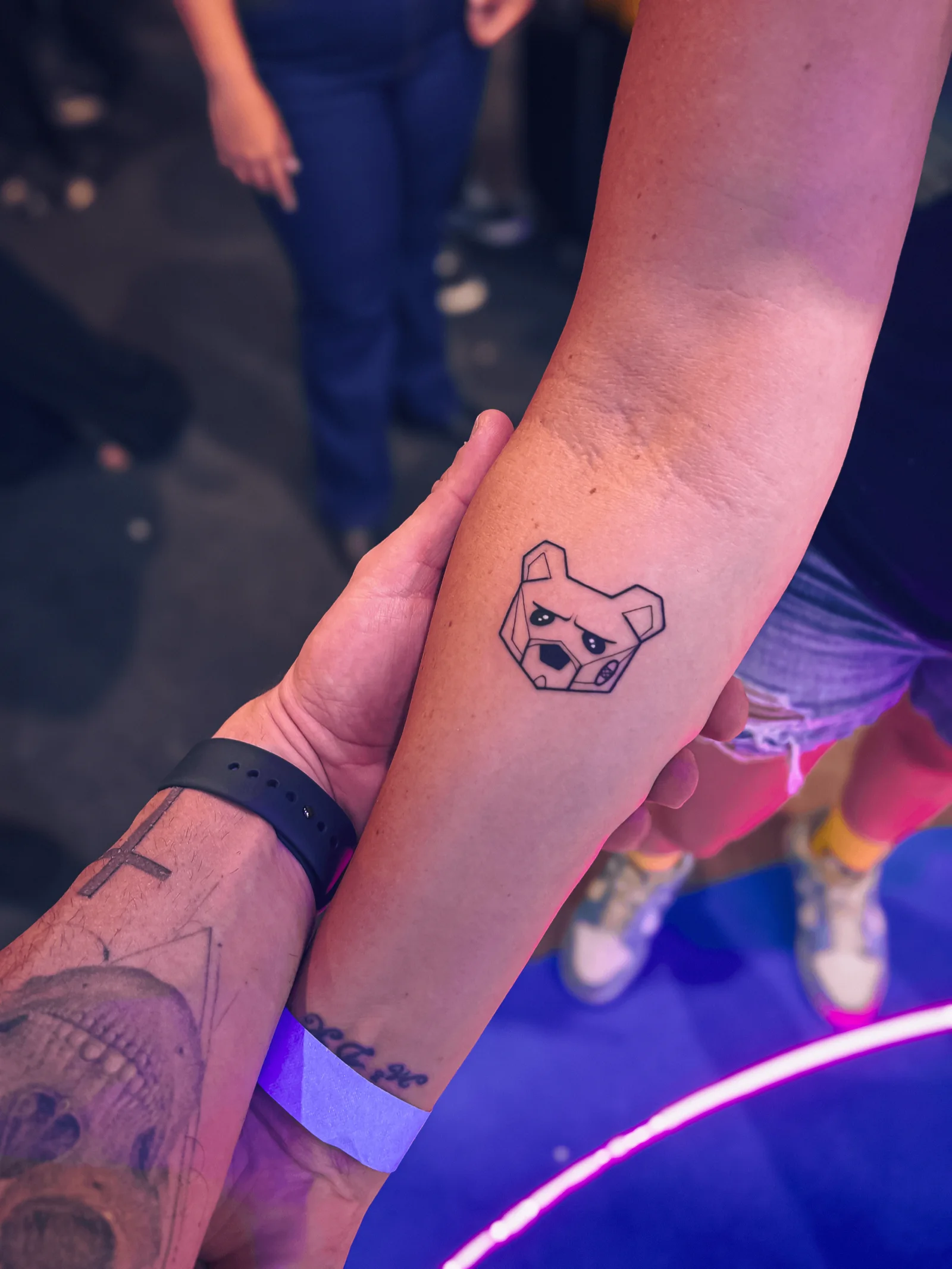 Will Jardim segurando o antebraço de um fã que tatuou o urso mascote da Under Labz
