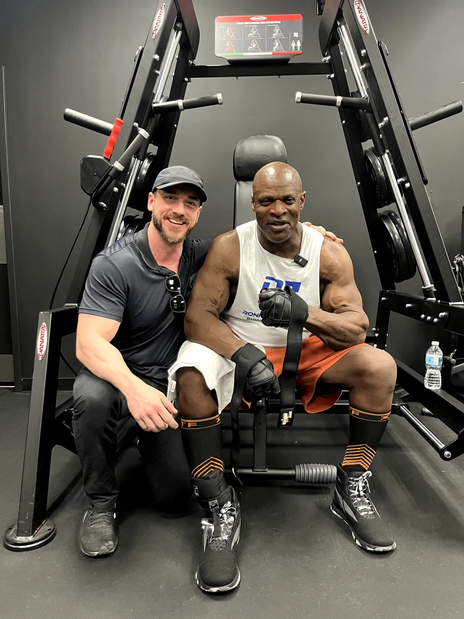 Will Jardim sorrindo ao lado do bodybuilder Ronnie Coleman em equipamento de musculação