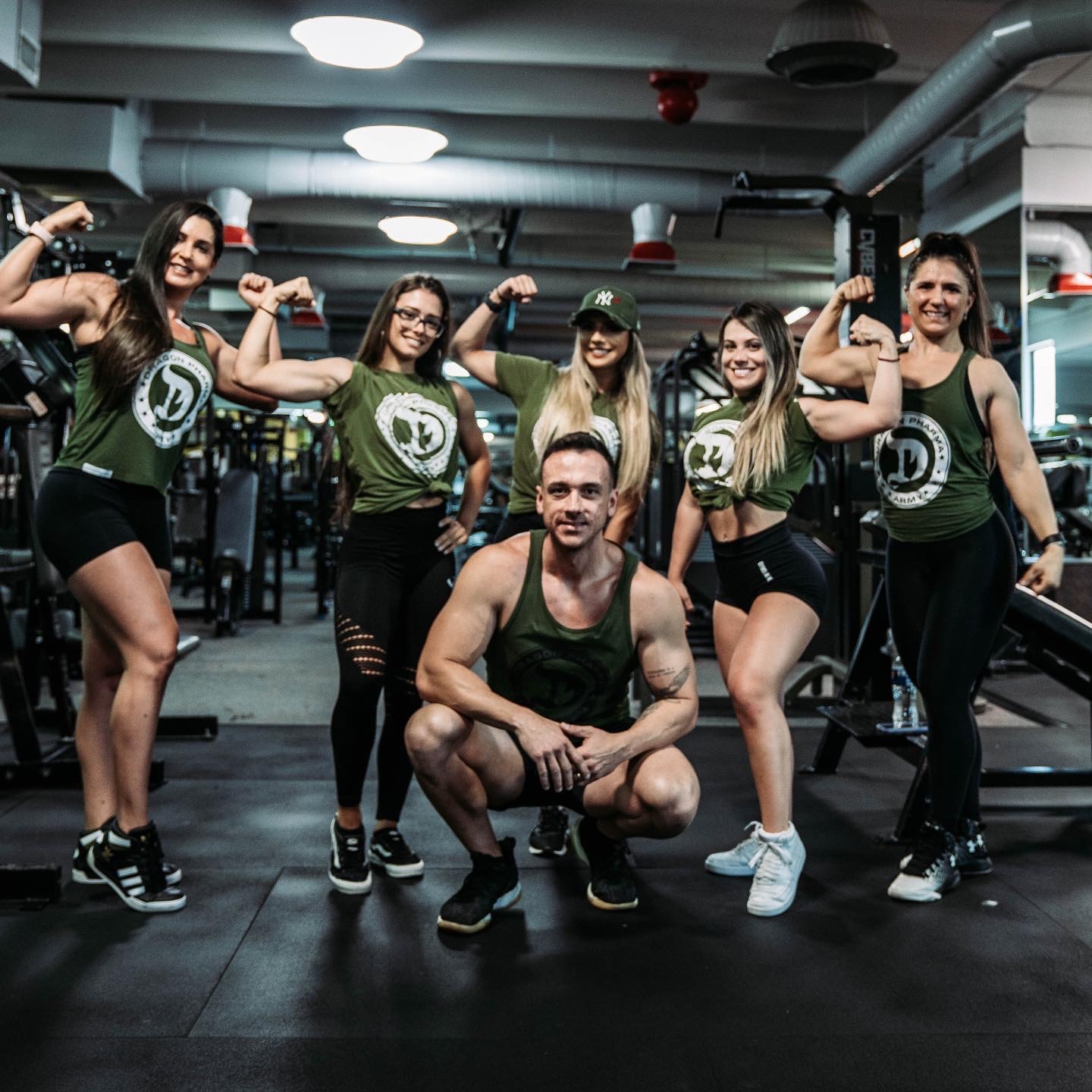 Will Jardim agachado à frente de um grupo de mulheres com camisetas Dragon Army na academia